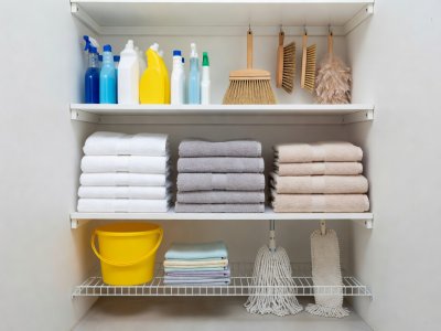Organized cleaning supplies and folded towels in a utility closet